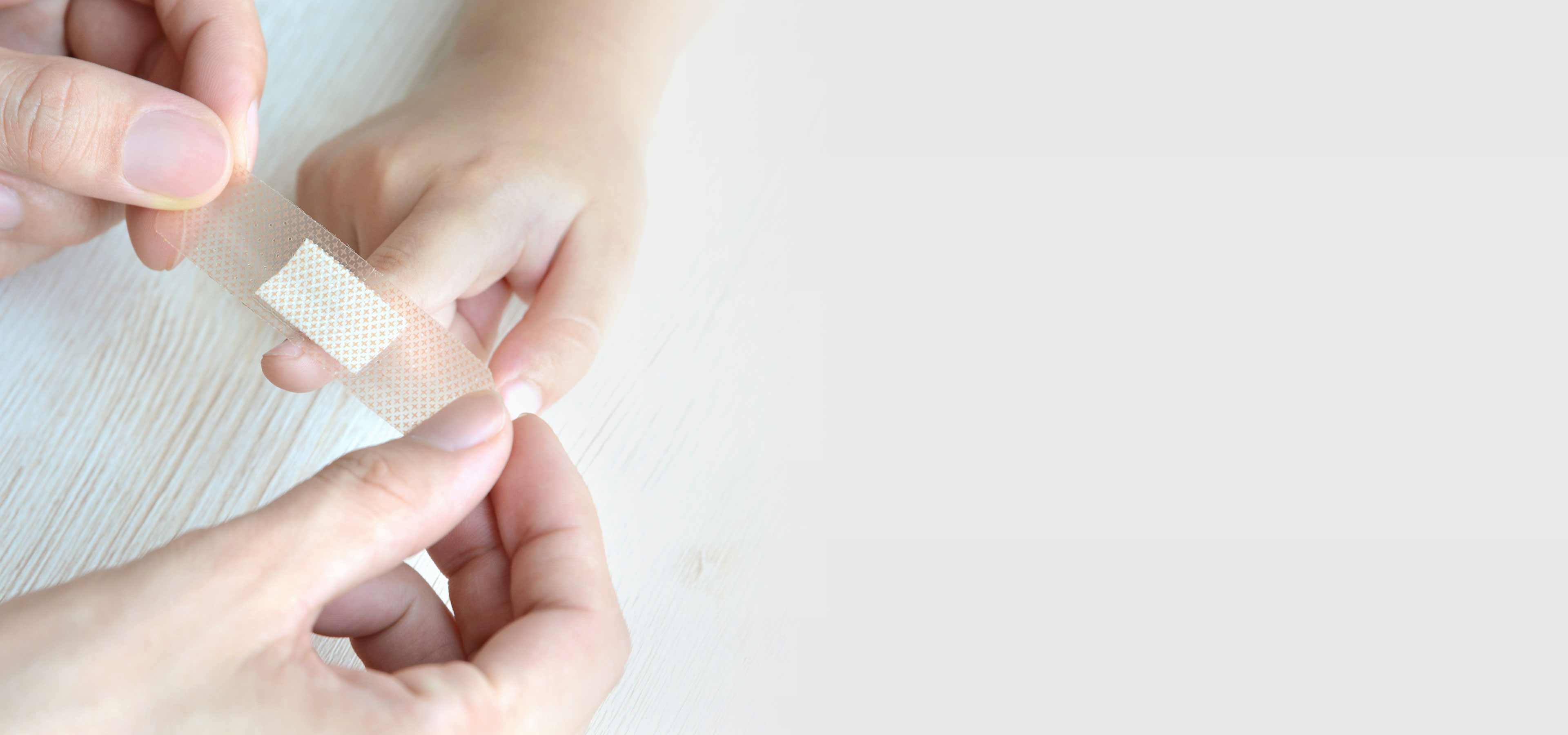 Eine Person klebt sich ein Pflaster auf einen Finger 