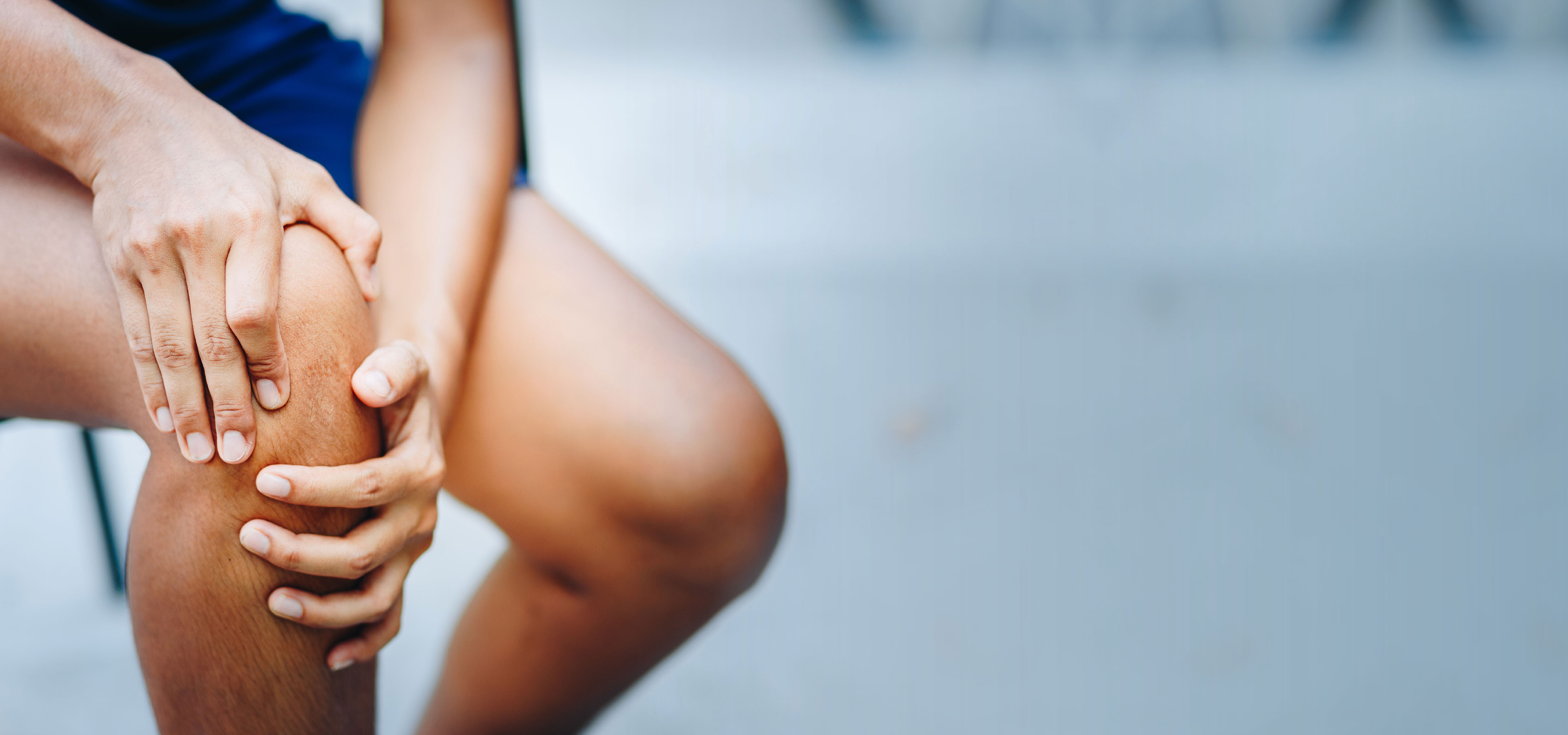 Schmerzendes Knie Eine Frau hält sich ihr schmerzendes Knie fest