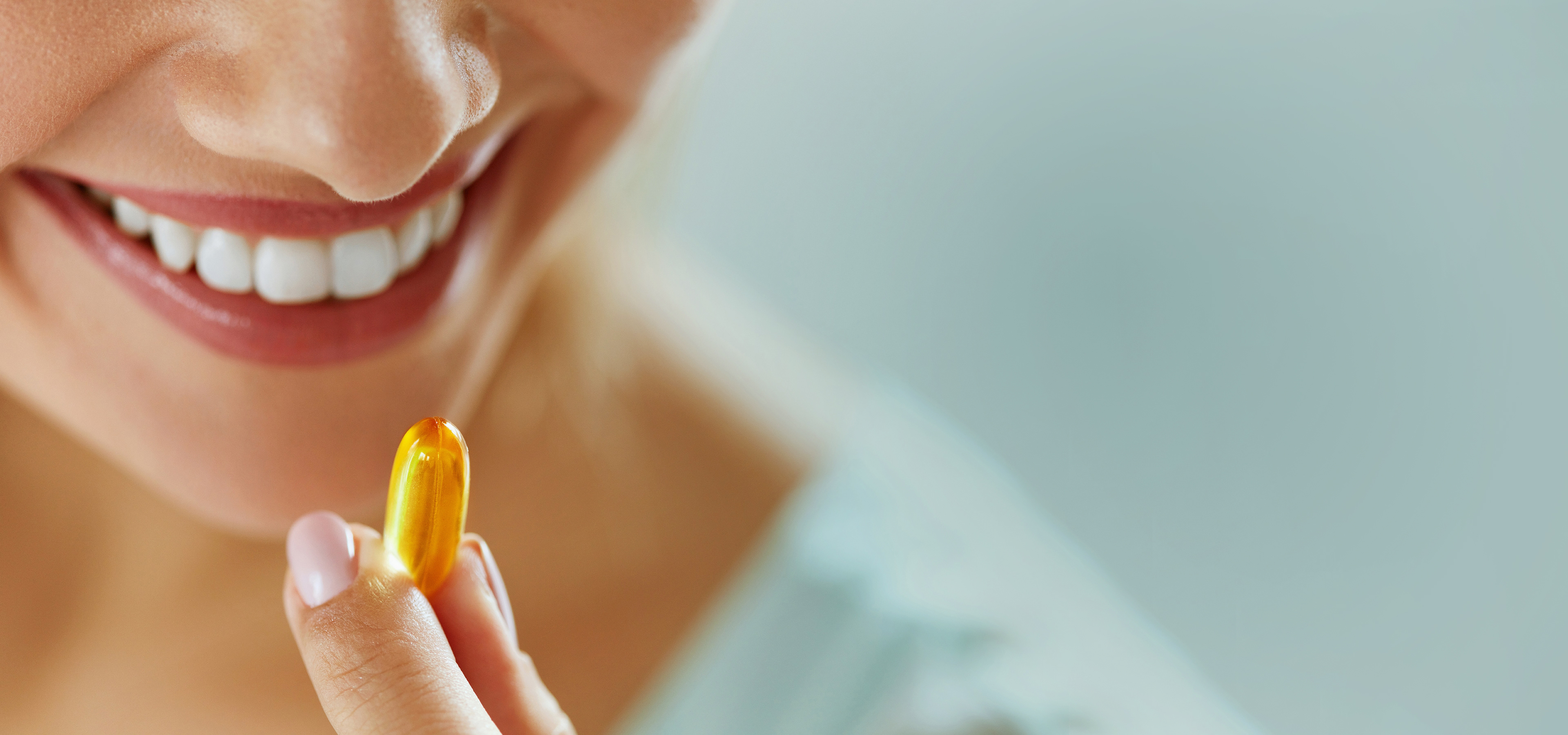 Nahrungsergänzung Kapsel Eine Frau hält eine gelbe Kapsel vor den Mund