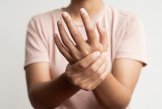 Nahrungsergänzungen Eine Frau in rosa T-shirt hält sich eine Hand fest