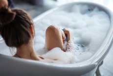 Ätheria® Gesundheitsbad Frau liegt in einer Badewanne mit Schaum