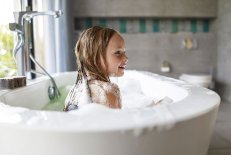 Ätheria® Kinderbad Ein Kind sitzt in einer Badewanne mit Schaum